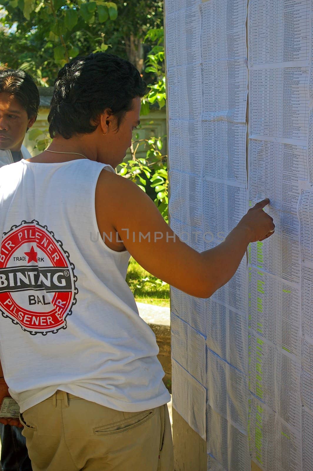 A young man searching for his name on a registration list on the day of the Presidential election. Tuban Bali, Indonesia. July 8, 2009.