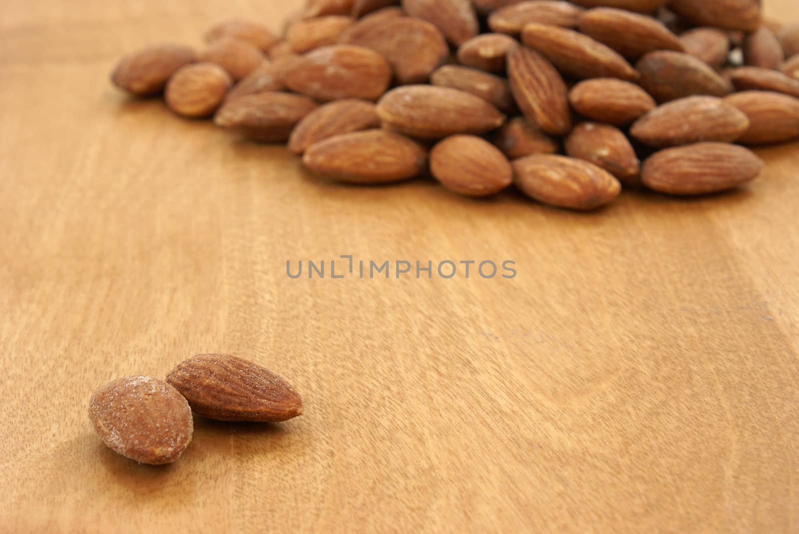 A heaping pile of almonds behind two that are away from the rest.