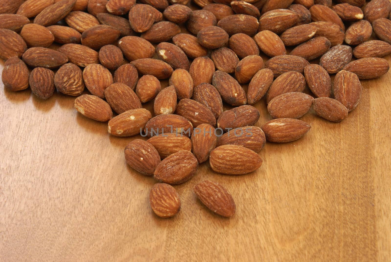 A pile of almonds on a wood background.