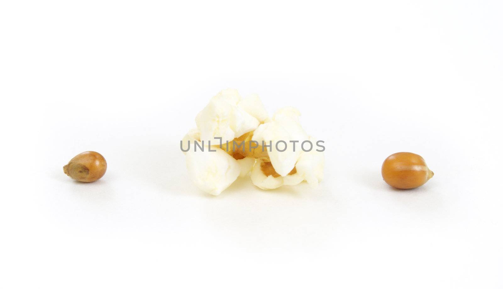 A piece of popped corn with two kernals beside it.