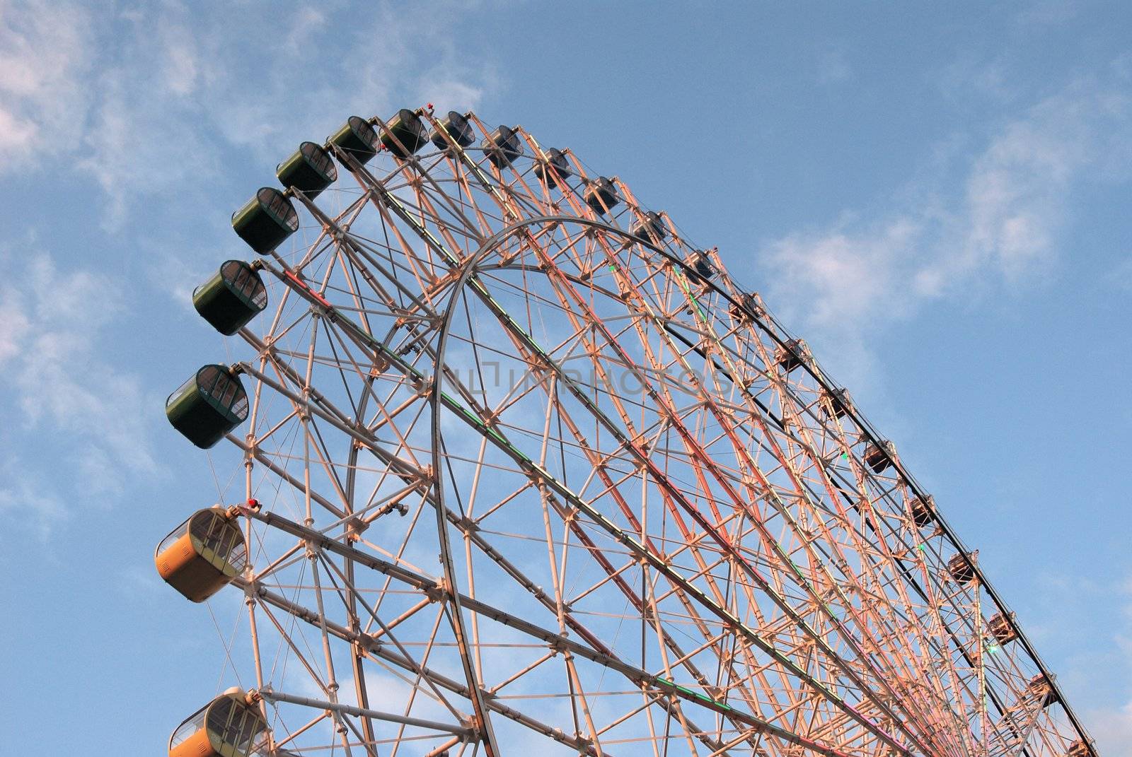 Tall angled view of ferris wheel against whispy clouds