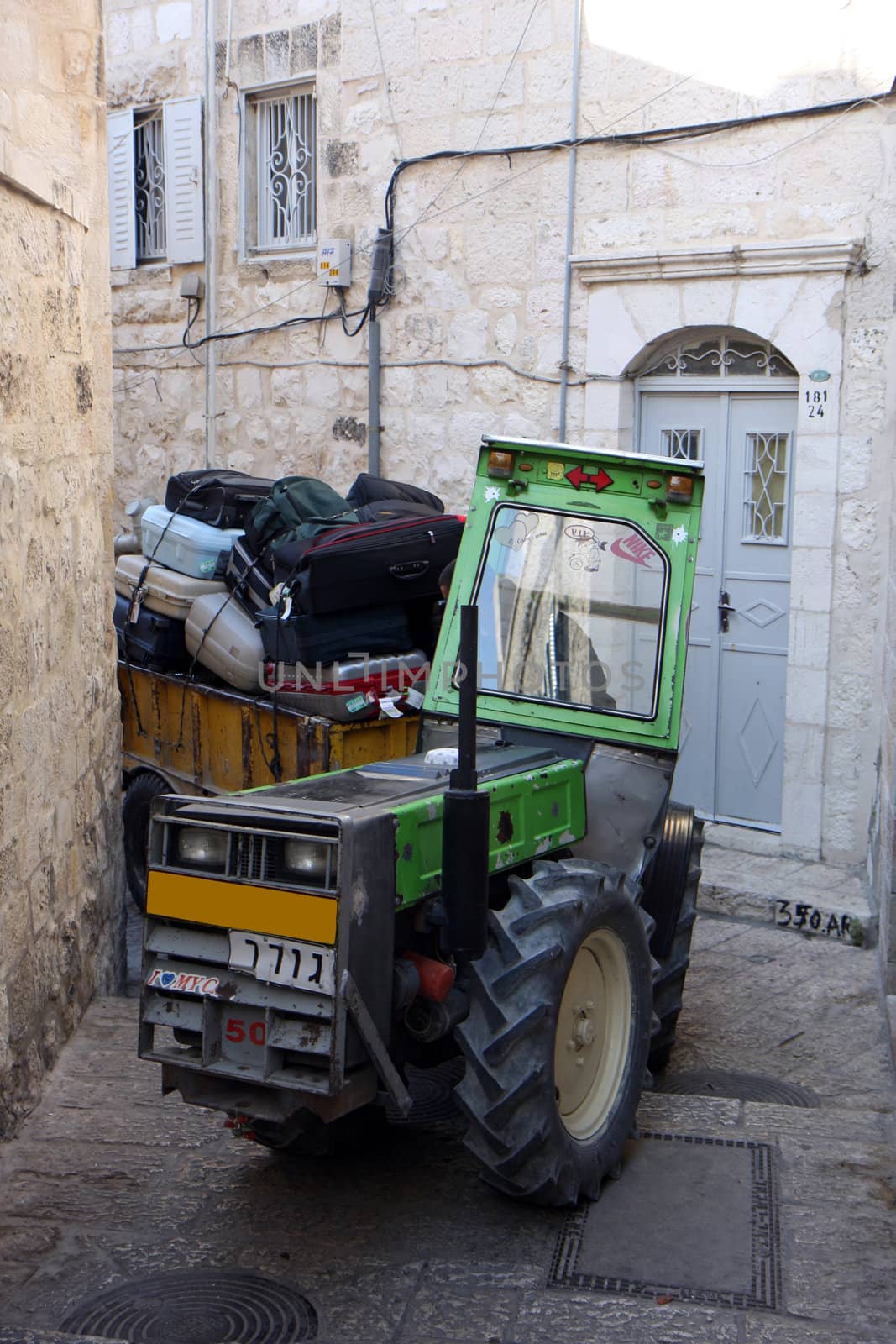 Tractor moving tourist's luggage at narrow Jerusalem streets