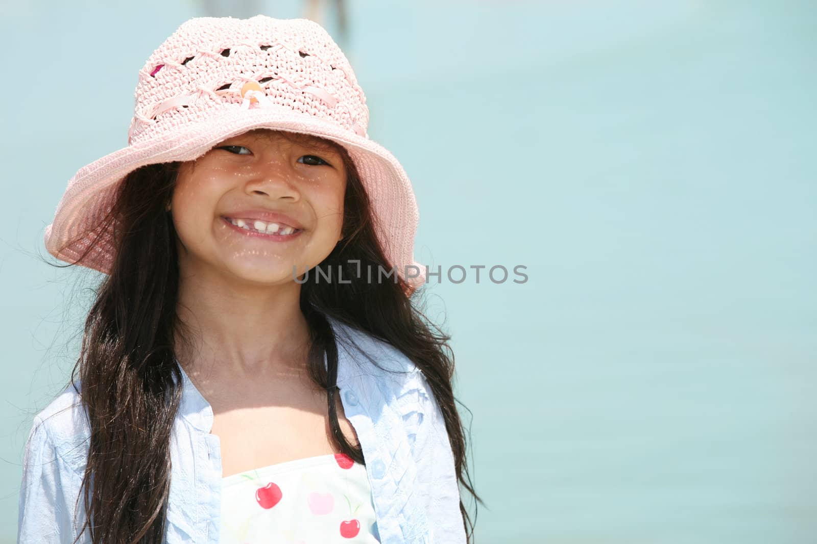 Cute little girl in pink hat at beach