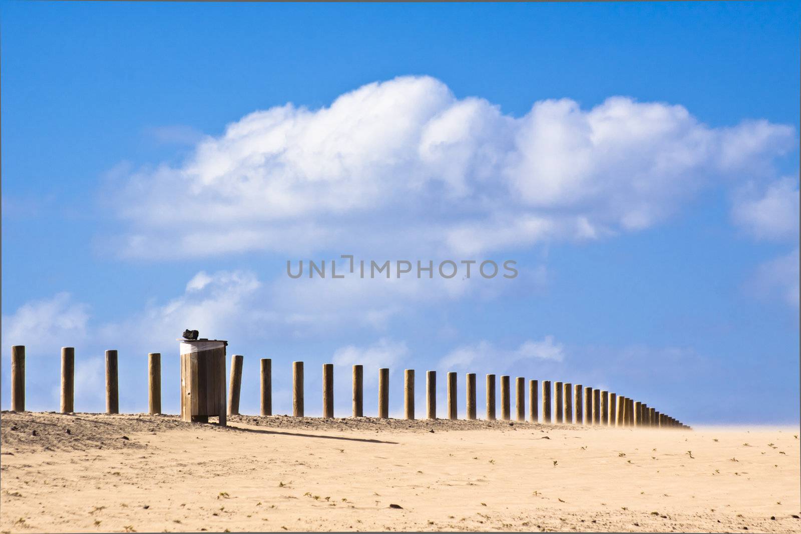 Wooden waste bin along the road dissapearing into the infinity of the dessert.