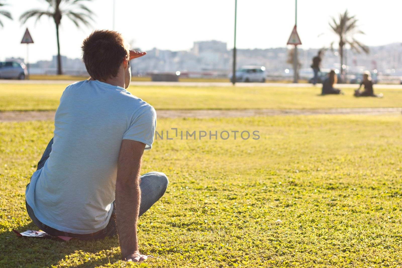 young man sitting on the grass and waiting