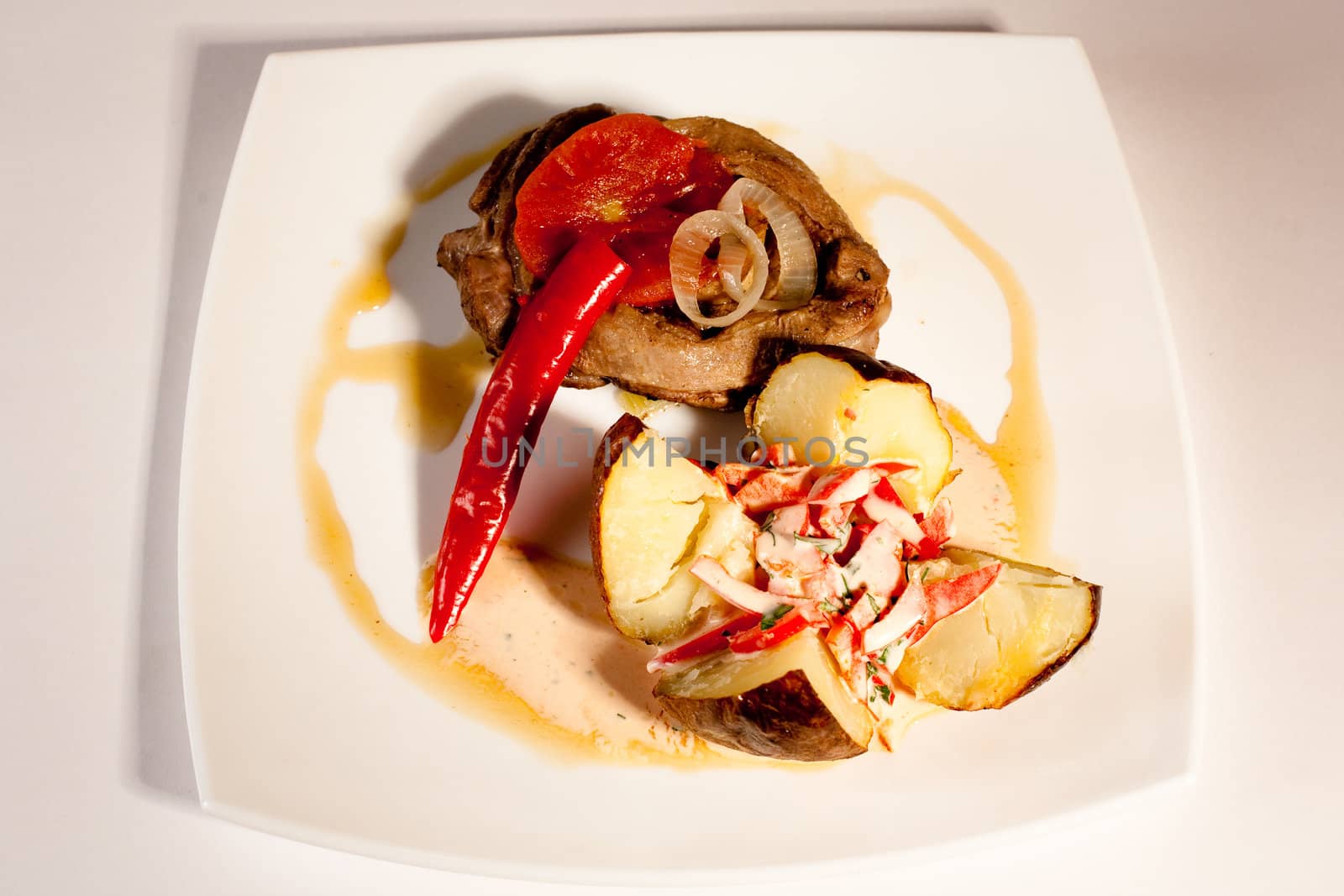 meat and potatoes with vegetables on a white plate
