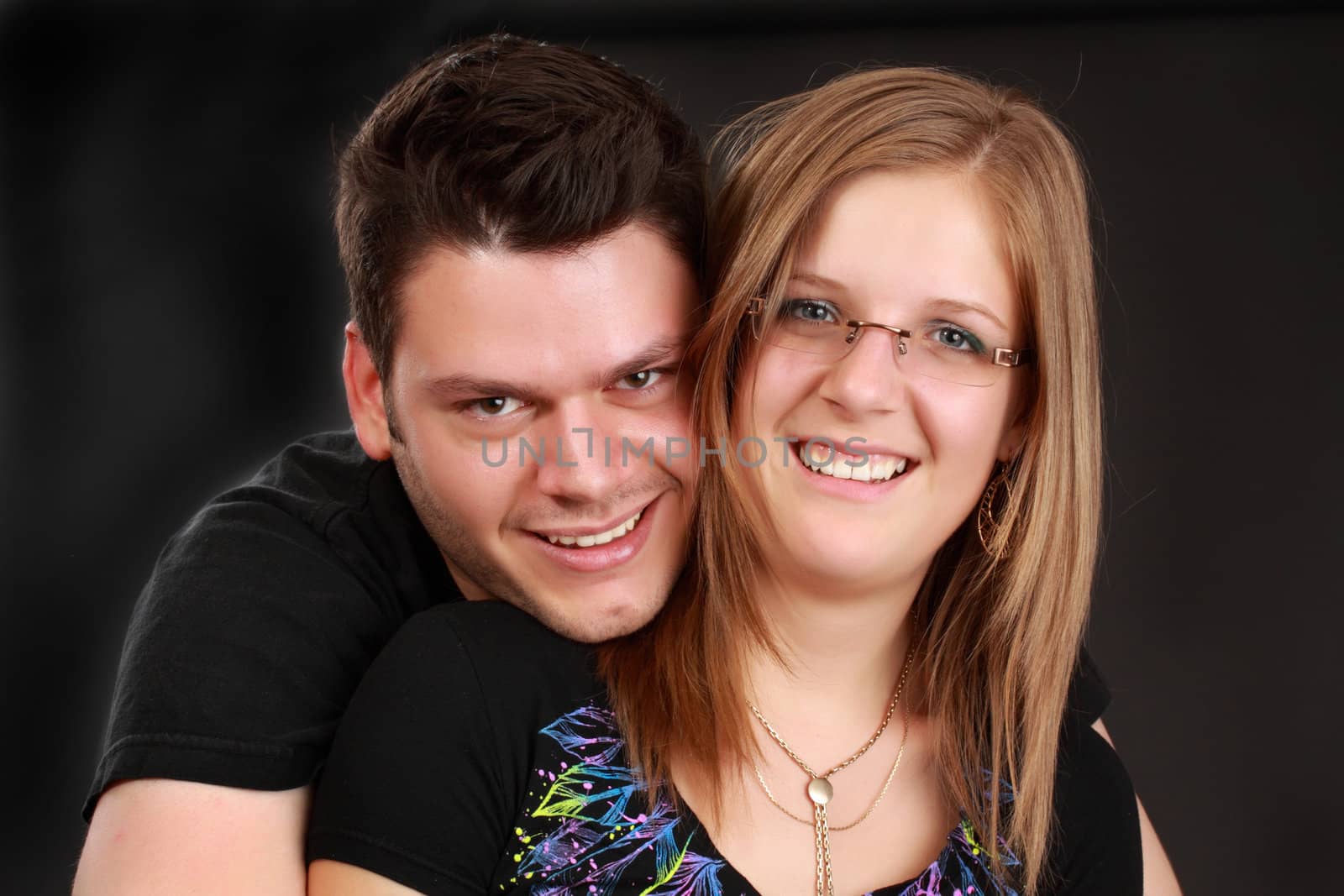 portrait of a young caucasian couple, black background