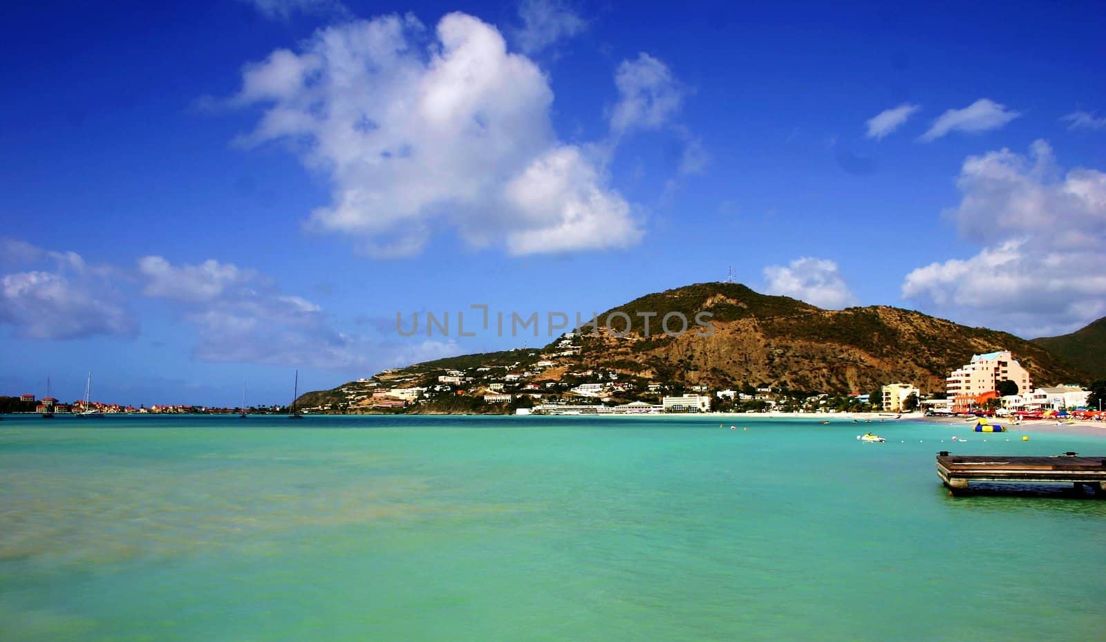 Mountain on St-Martin coastline with green sea.