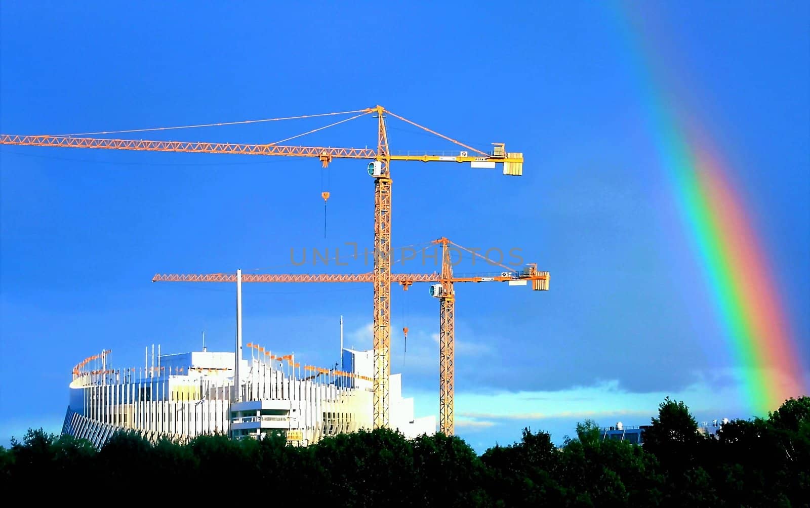 Rainbow over cranes on construction site