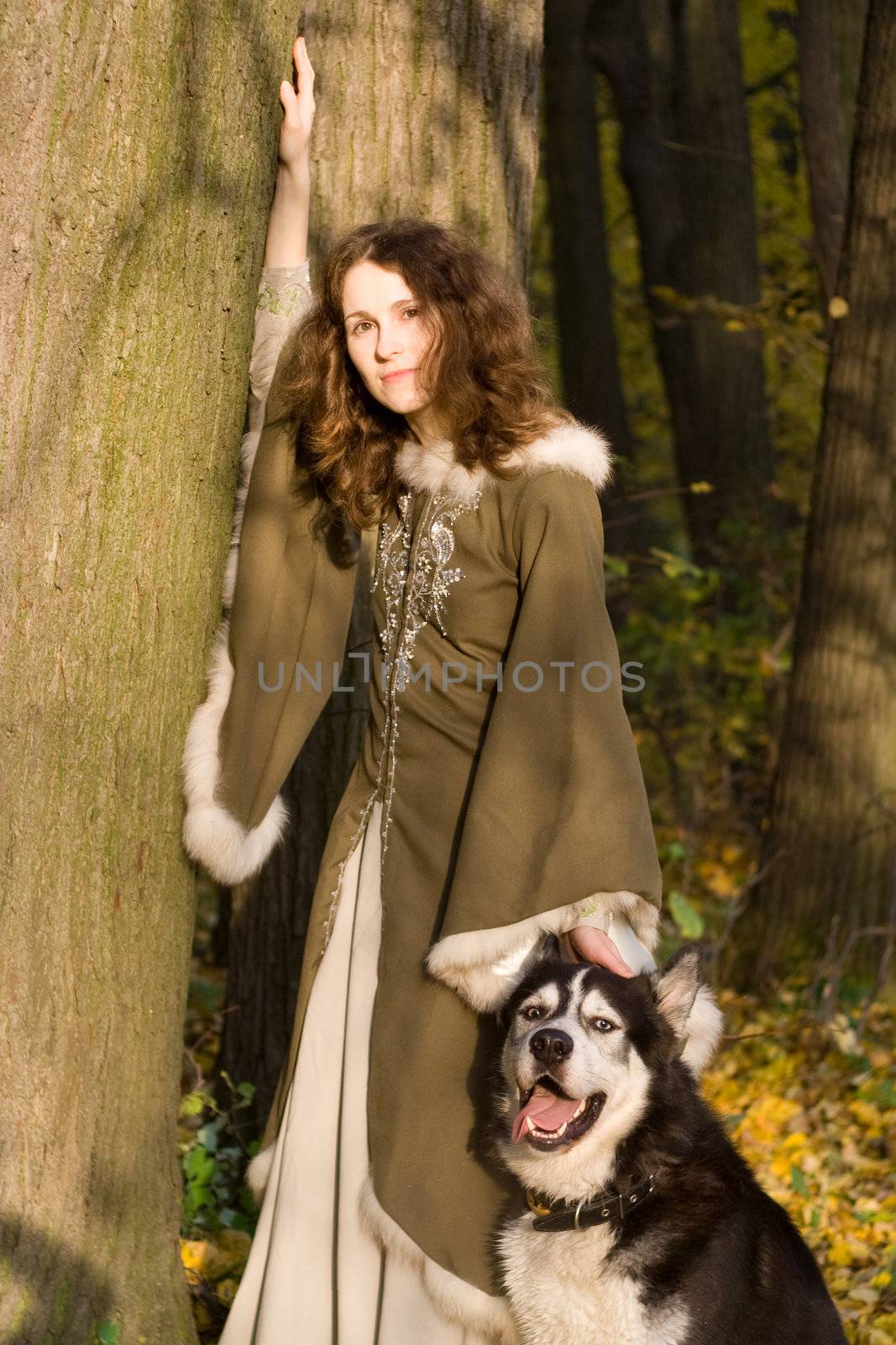 Lady in medieval dress and dog in the forest
