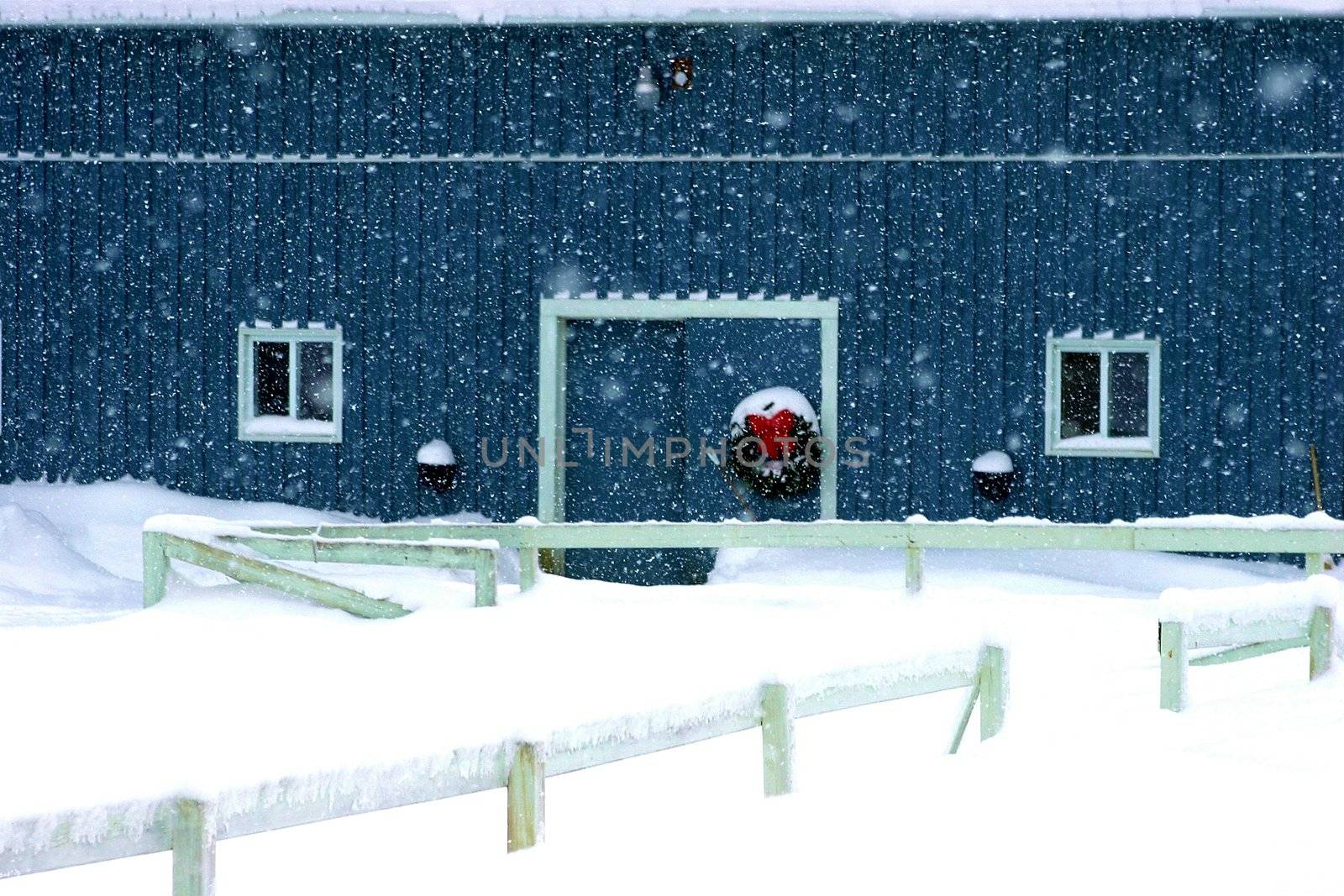 Christmas reef hanging on a barn door during a snowstorm
