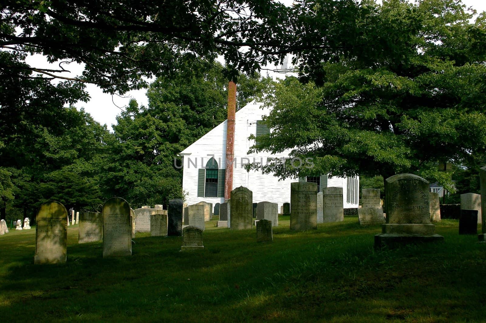 Head stones in cemetery on Maine coastline behind white church