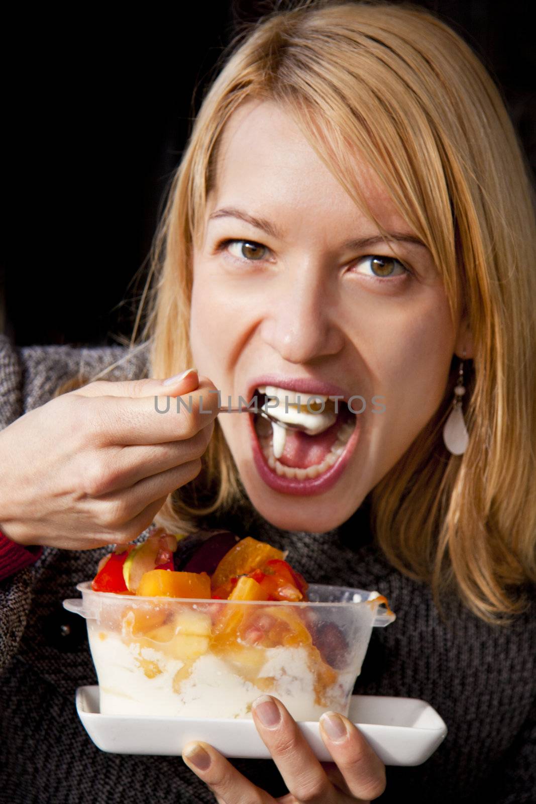 Young woman eating yoghurt with fruits