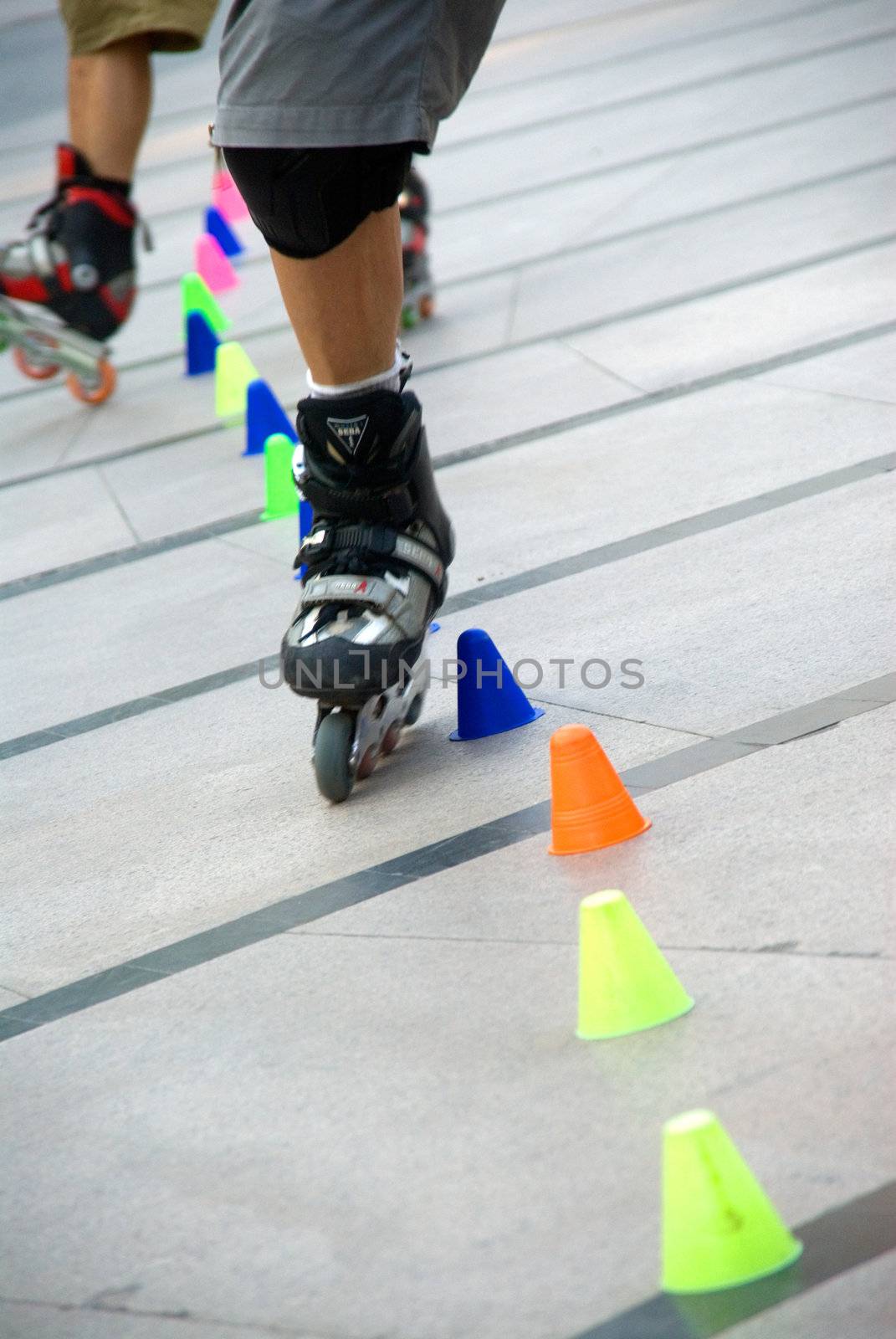 young guy skating slalom around colorfull cones