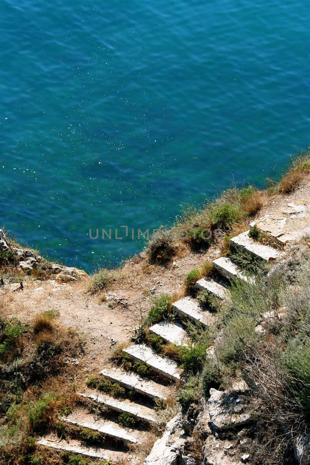 Stoned stairs leading to the sparkling blue sea. A romantic summer scenery