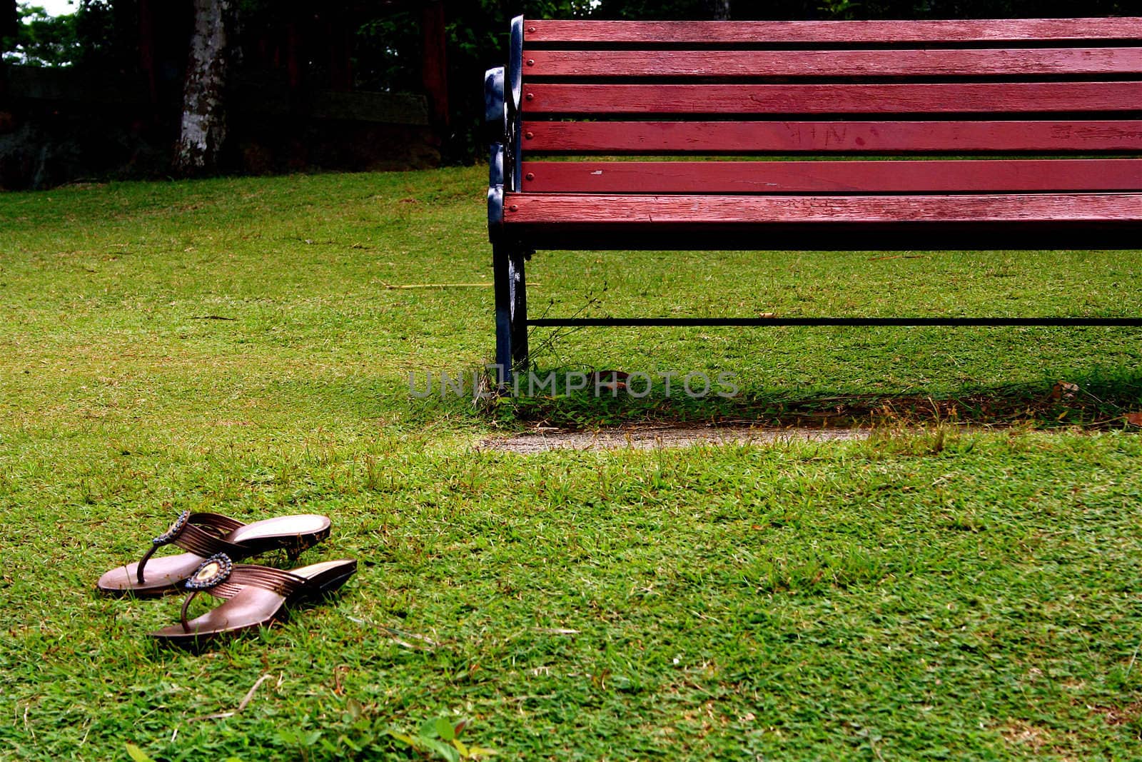 Single bench staying on the hill with the sandals left nearby
