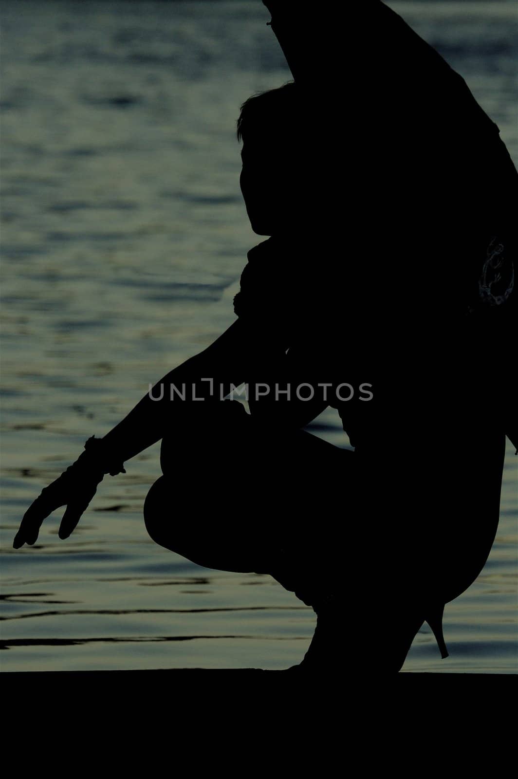 Figure of a slim lady with umbrella near the river