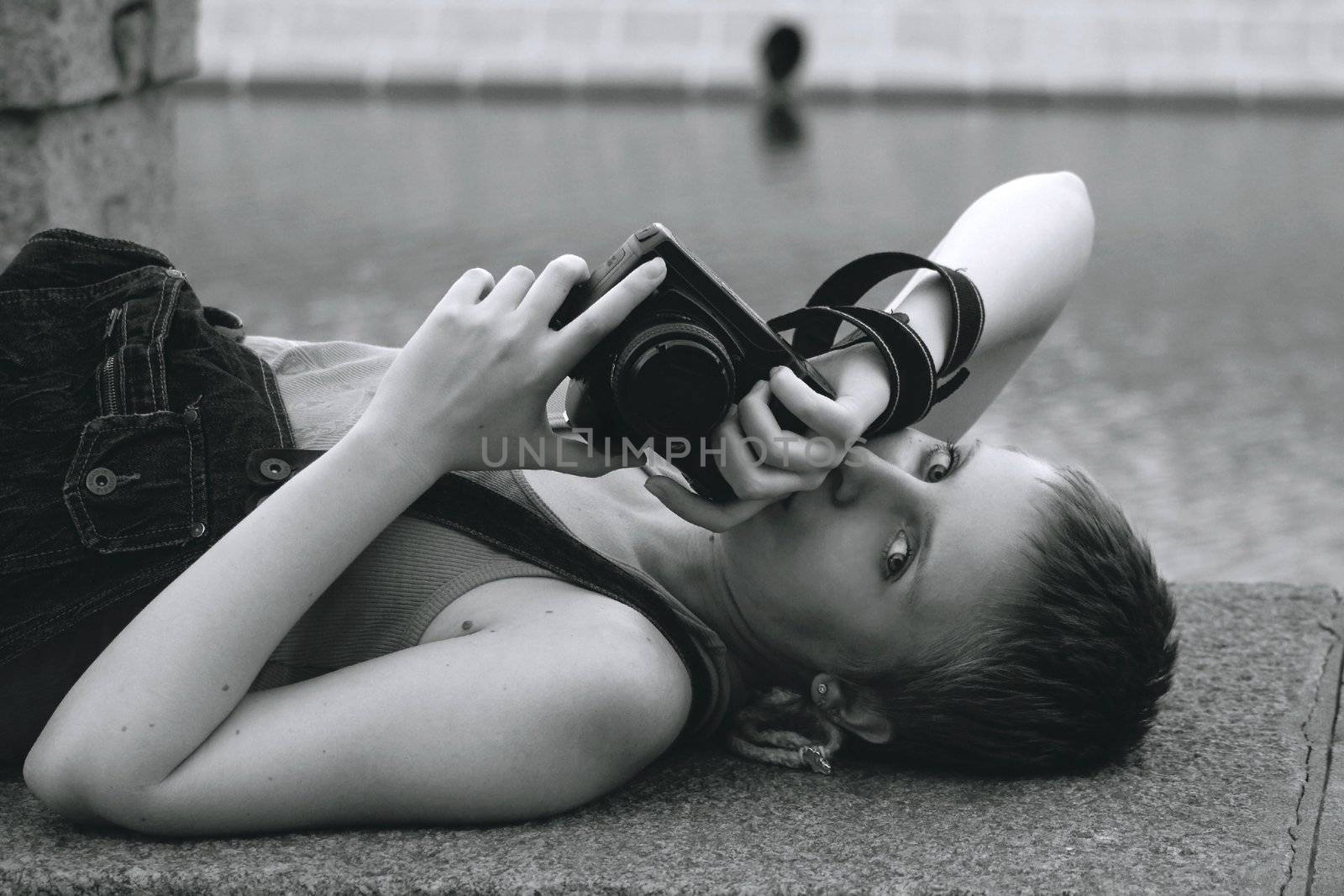 Young sexy woman with the camera lying near the river