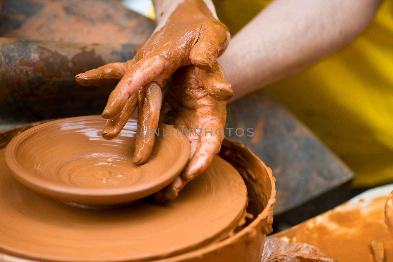 potter shaping a ceramic plate on a pottery wheel