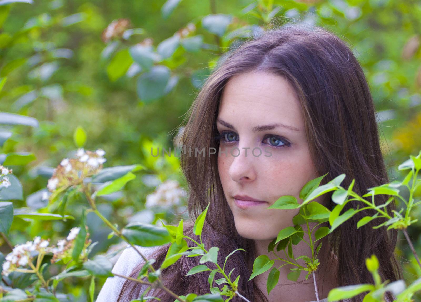 Young attractive woman portraited in the greenery of the city park.