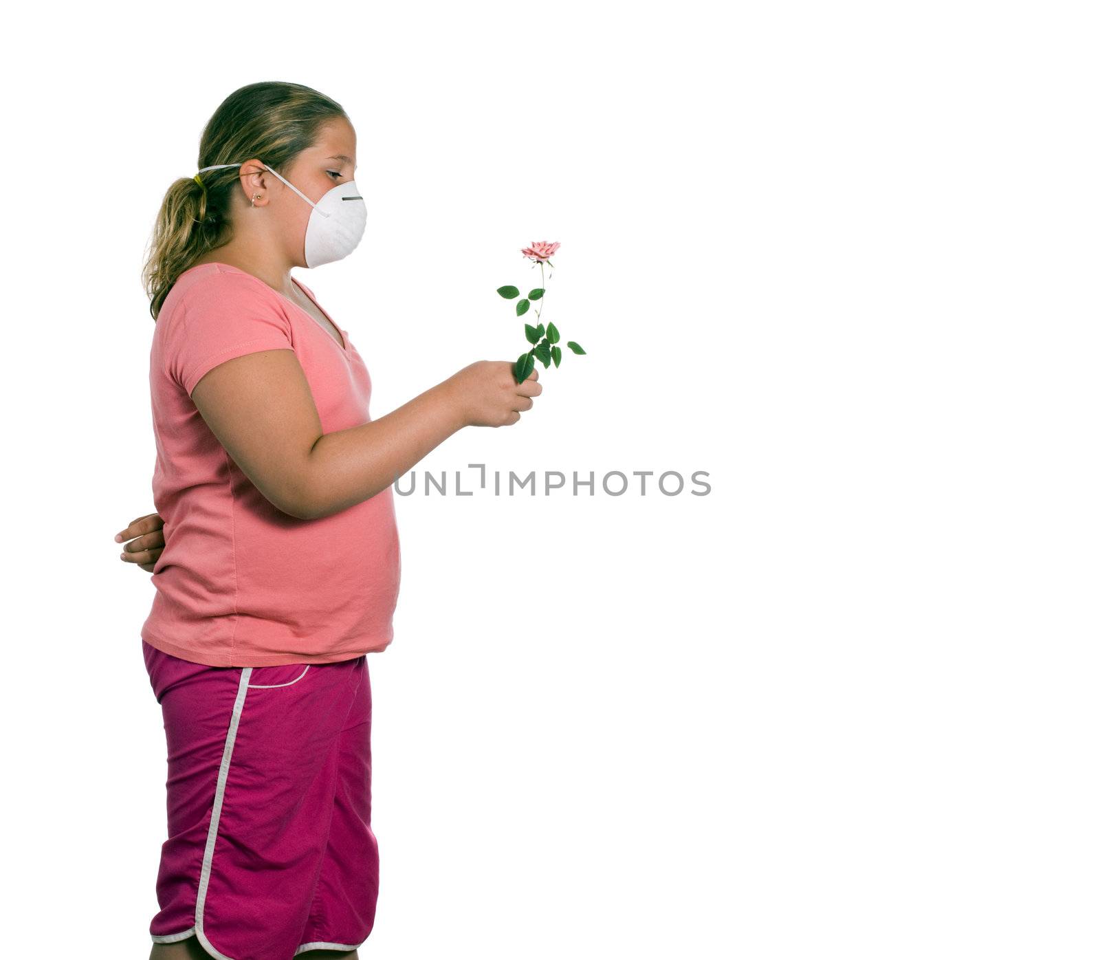 A young girl holding a flower while she wears a mask, isolated against a white background