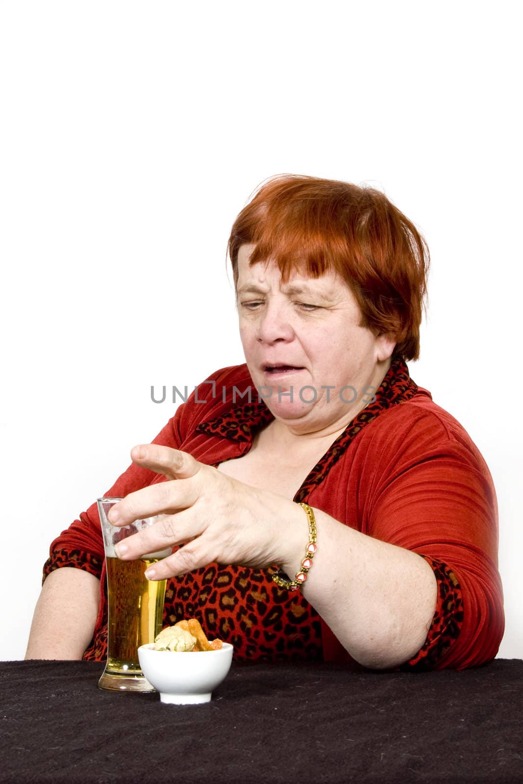 elderly female is drinking beer and eating a little bite on white