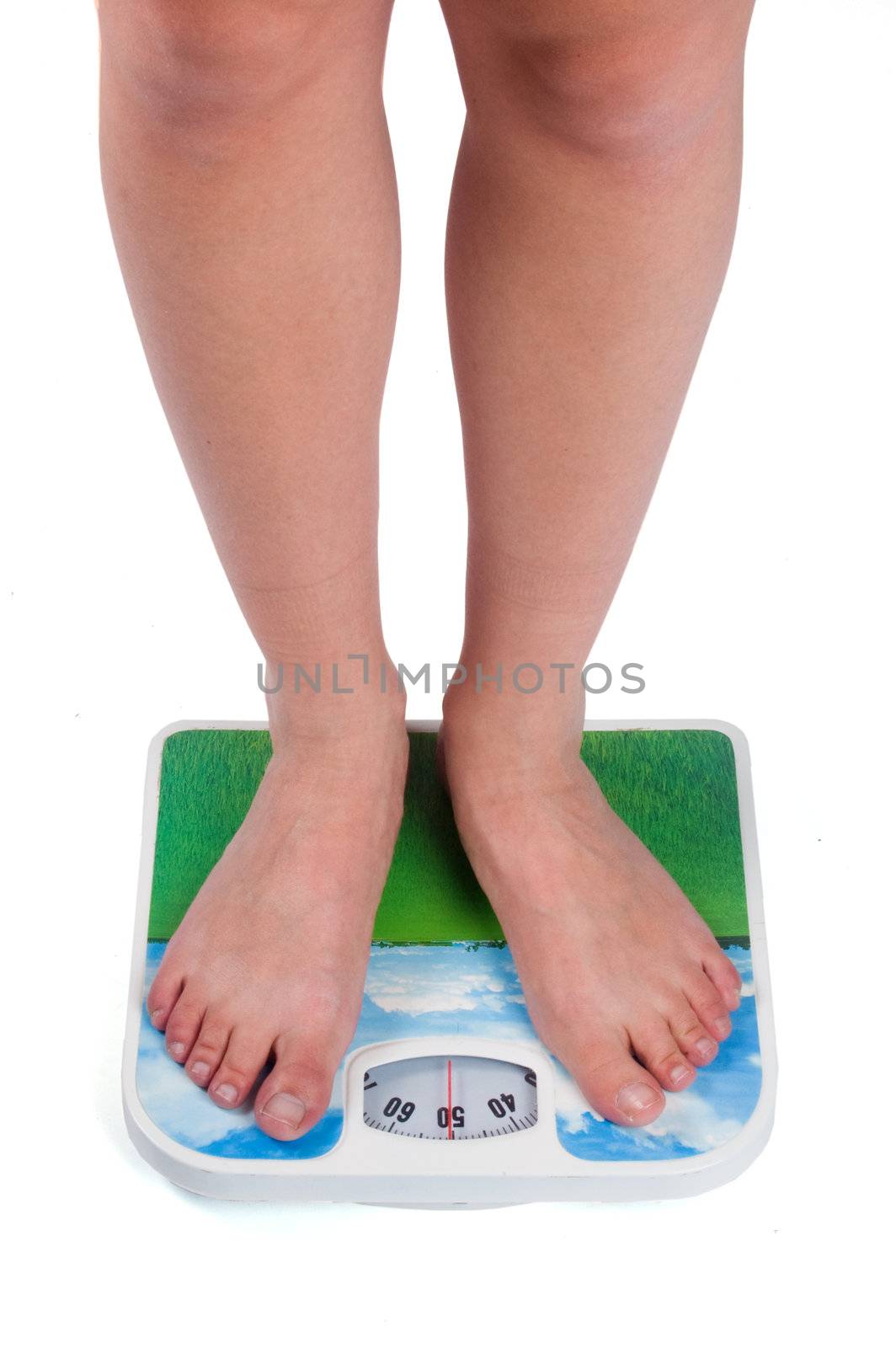 Leg of young caucasian female standing on bathroom scales, checking her weight


