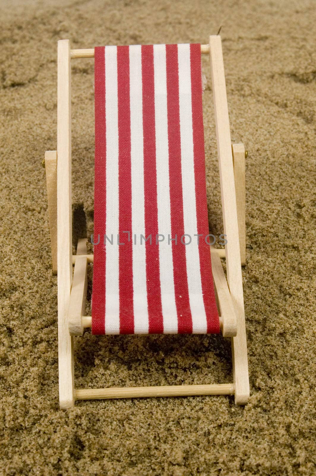 red beach chair on sand by ladyminnie