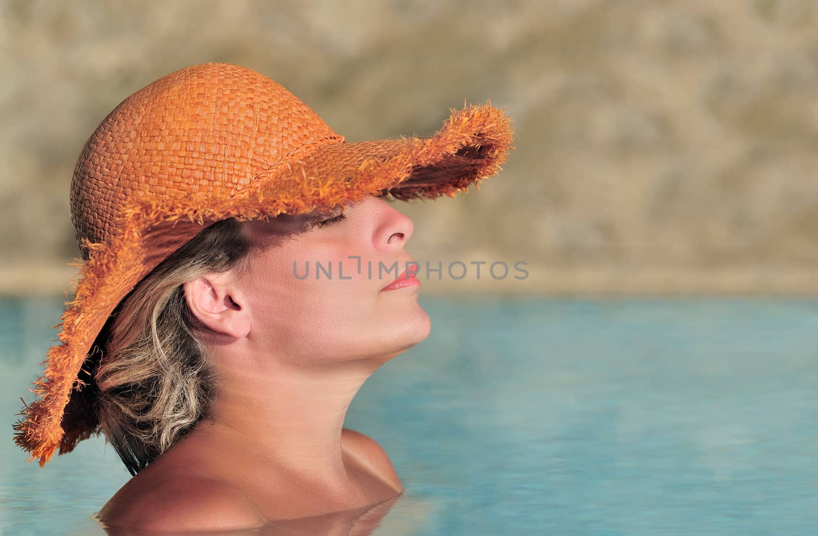 Young beautiful woman in a straw hat enjoying the sun in the pool