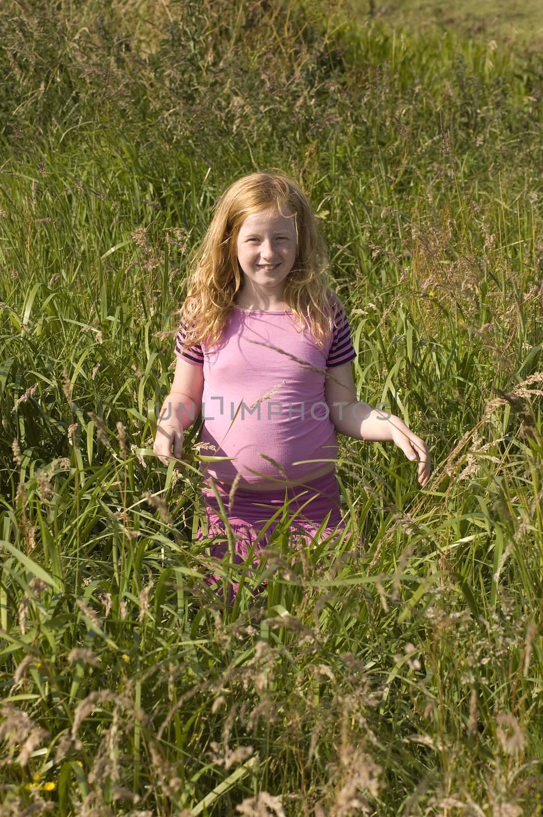little girl in pink clothes between high grass by ladyminnie