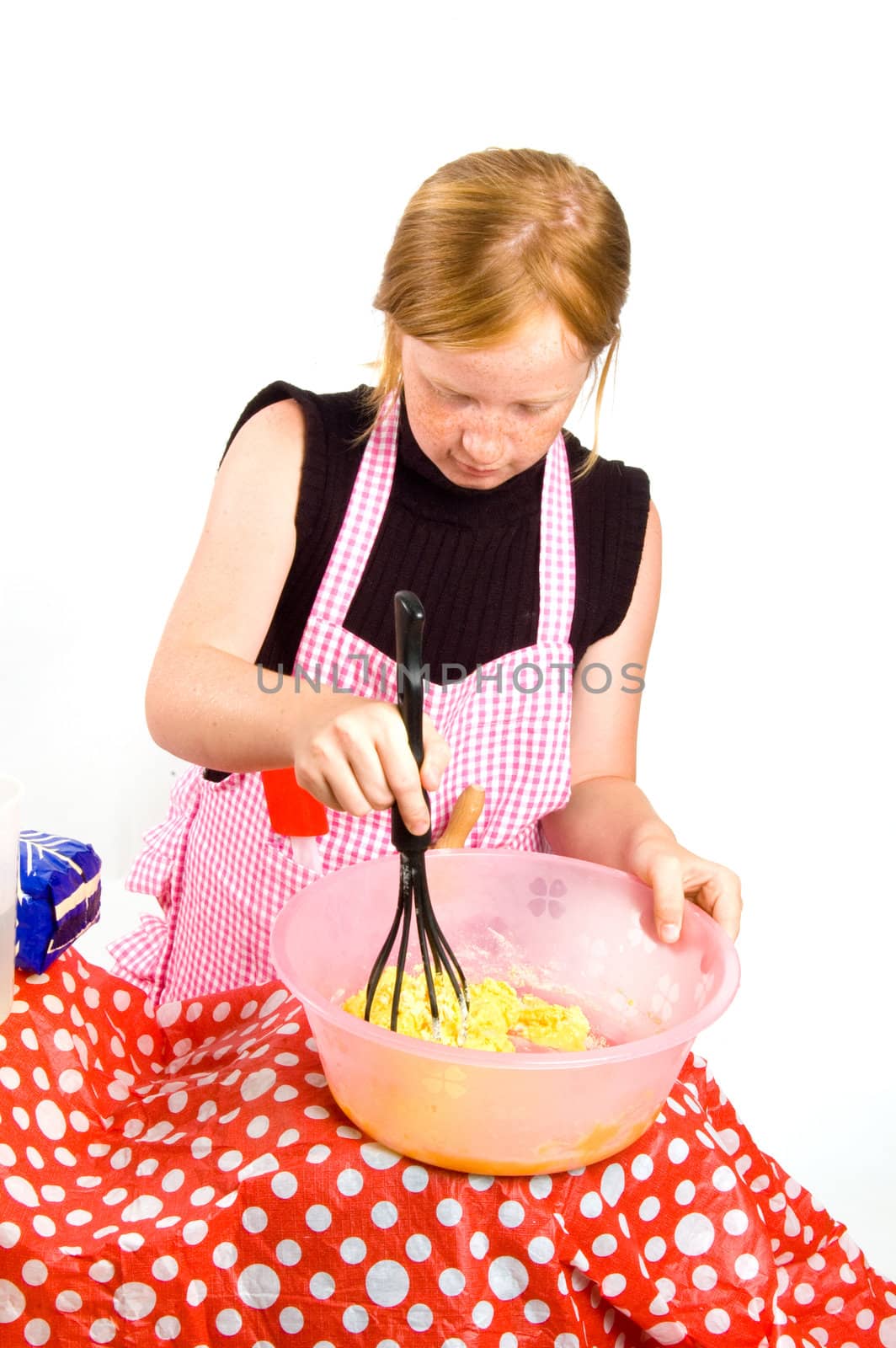 redhead girl is making pancake dough isolated on white