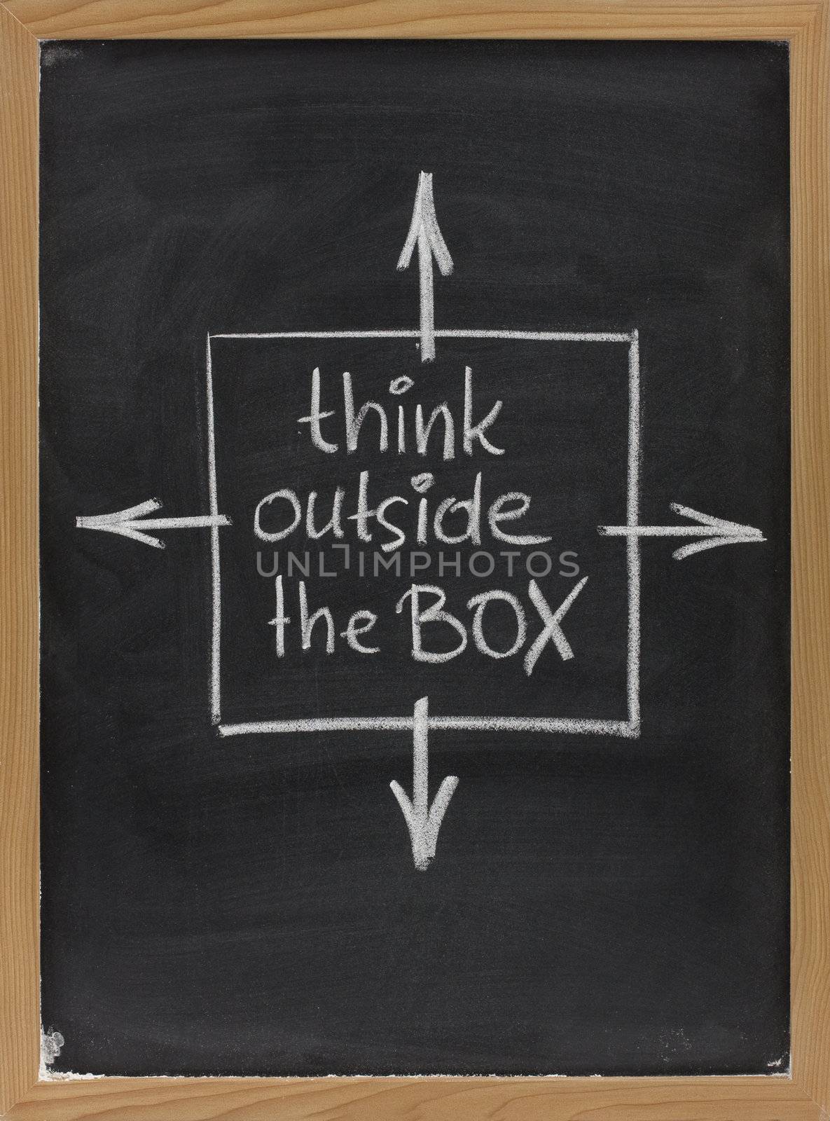 think outside the box - concept of different or unconventional thinking sketched with white chalk on a blackboard with eraser smudges