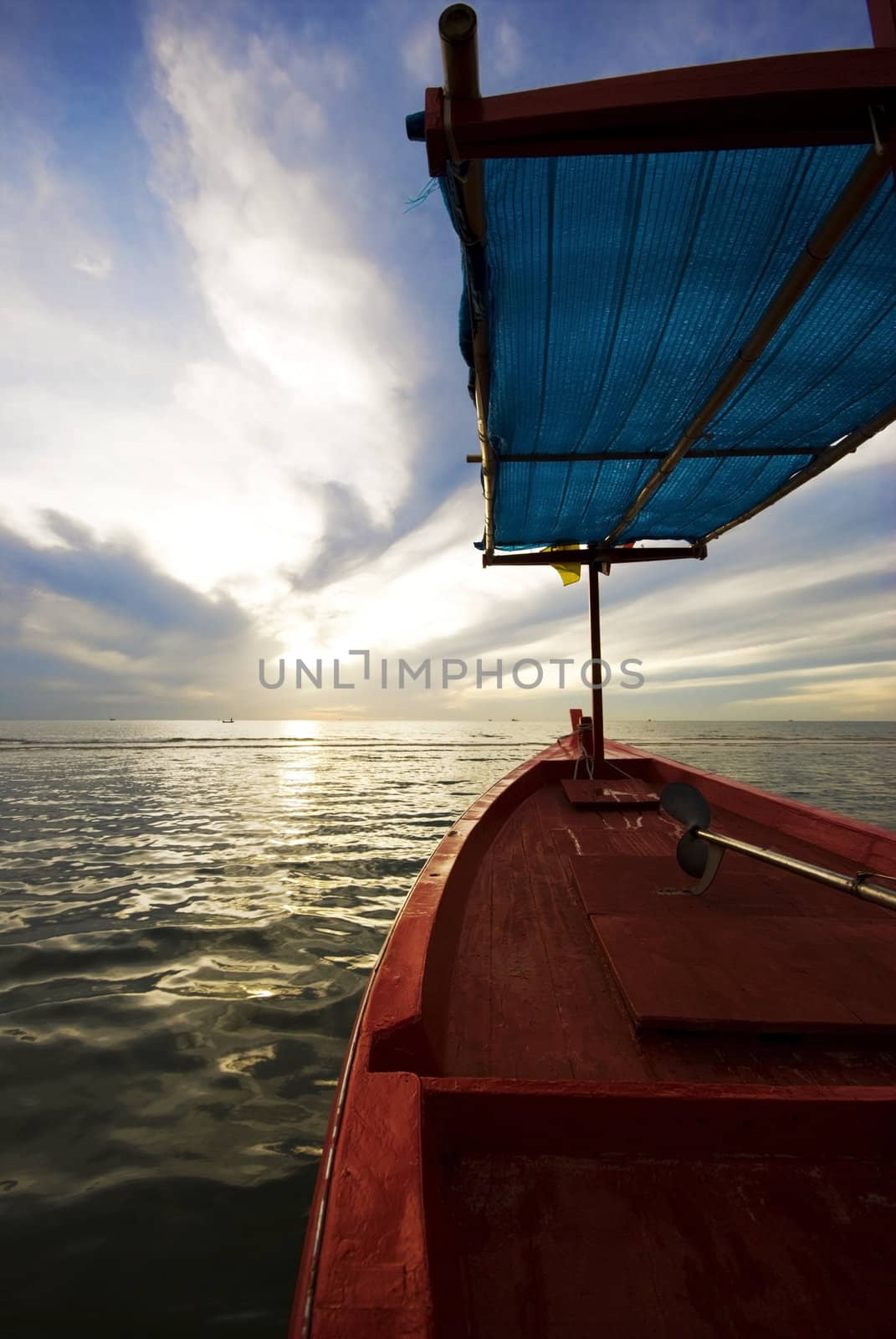 A red wooden fishing boat on the ocean at sunrise