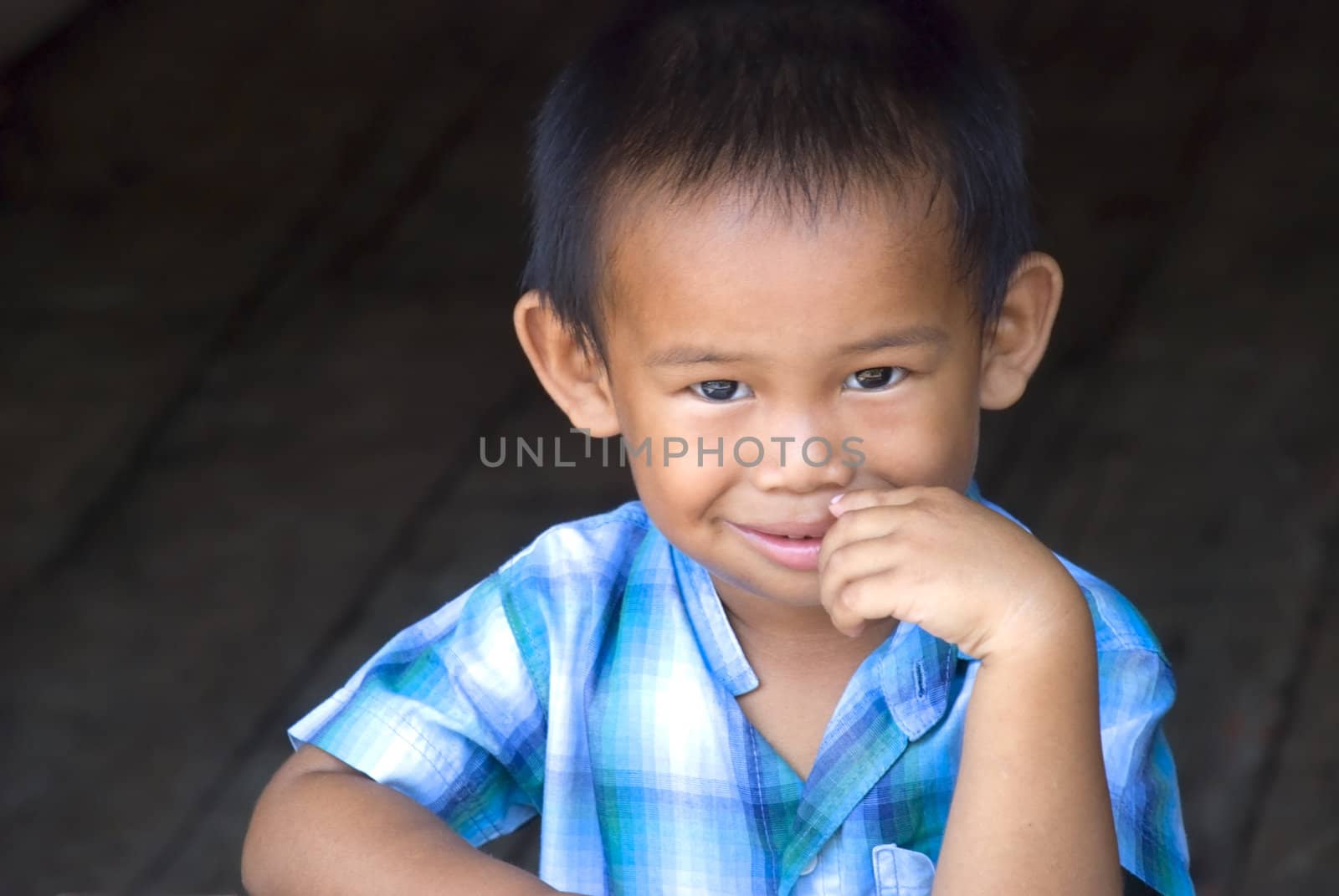 A young Asian boy wearing a blue shirt and smiling as he poses. Adobe RGB color profile.