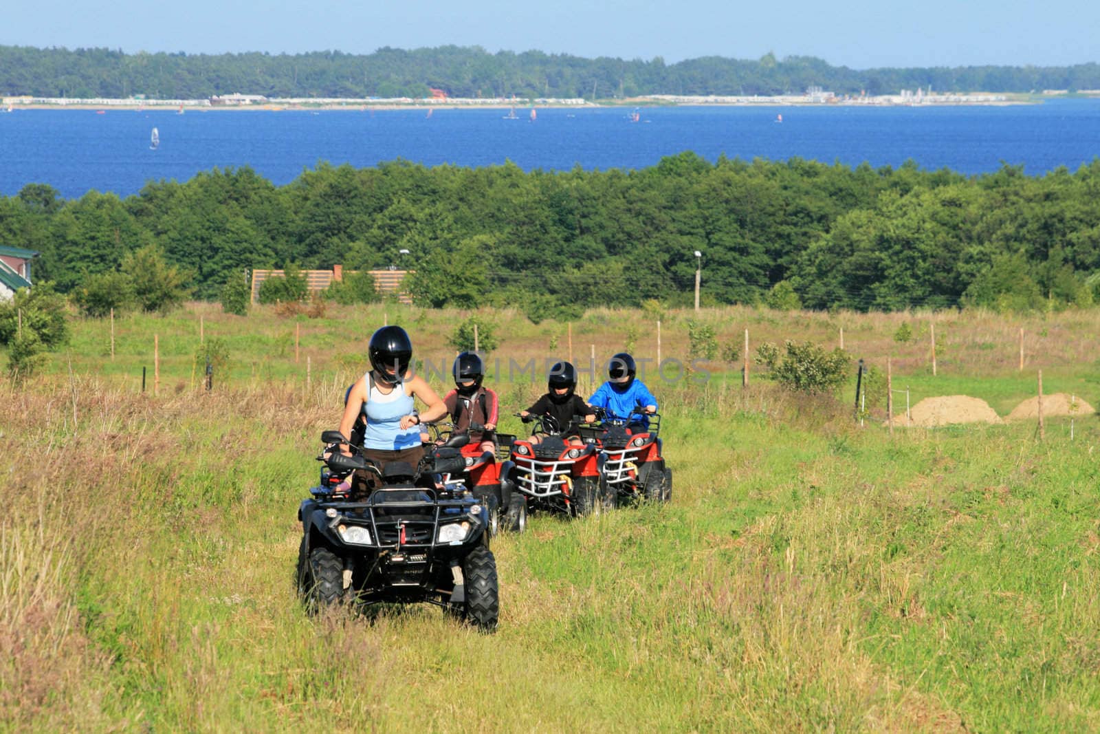 Group of young children riding quad / four-wheelers 4x4 on the meadow at the coastline
