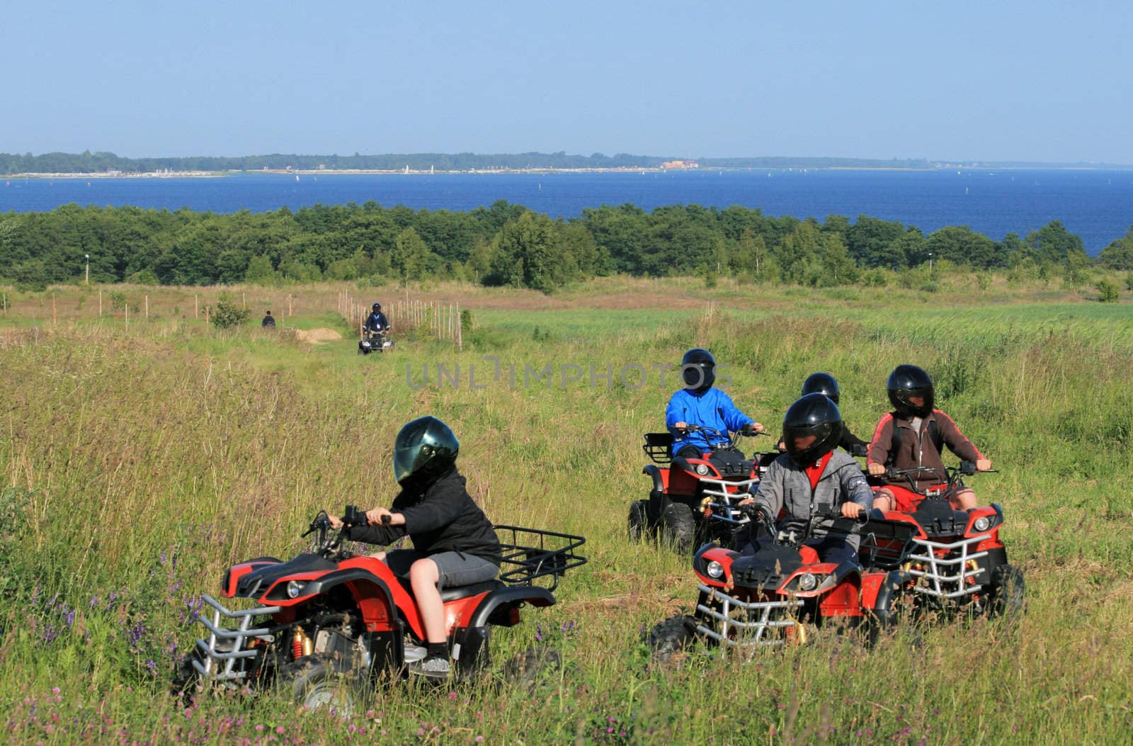 Group of young children riding quad / four-wheelers 4x4 on the meadow at the coastline
