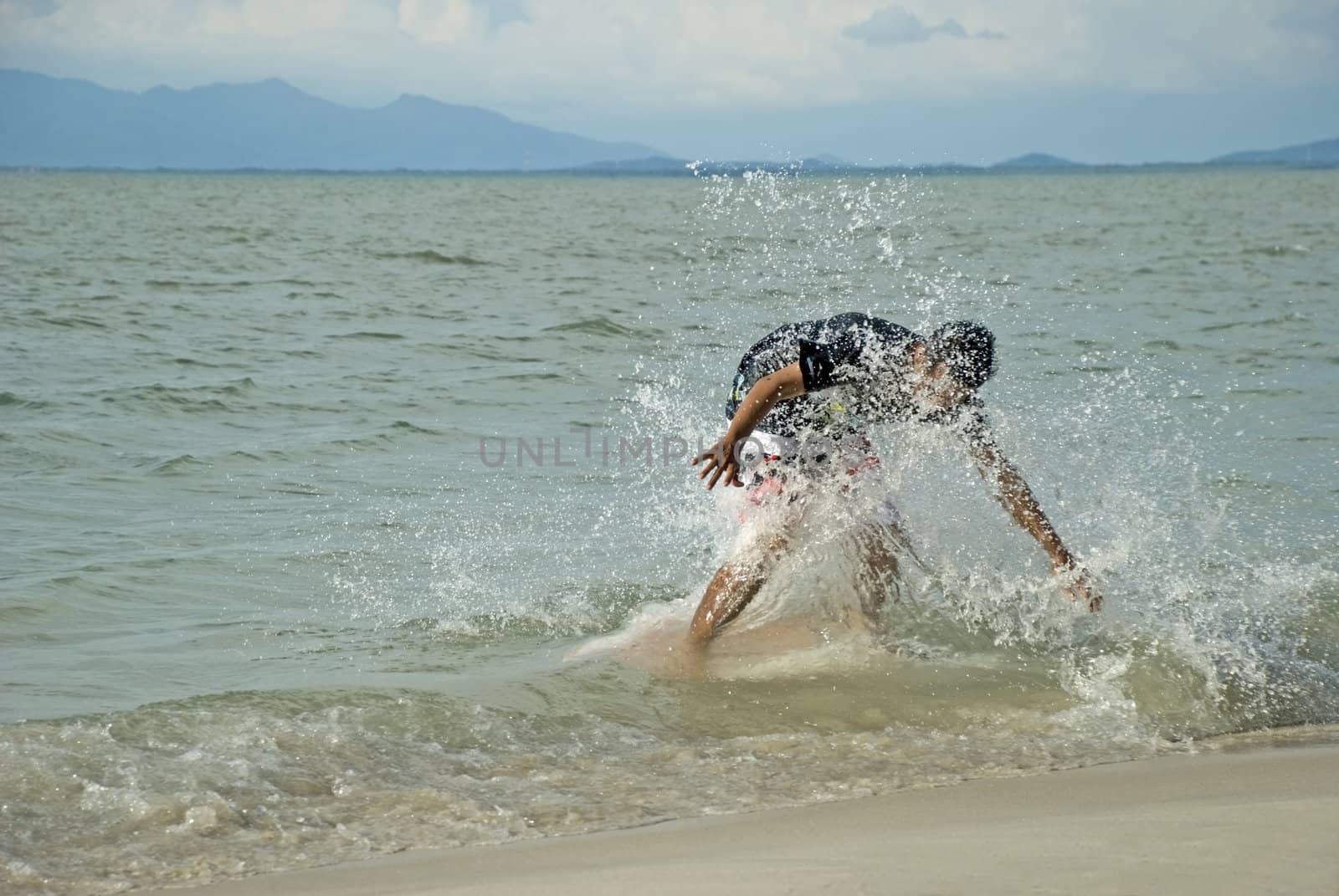 A young man skin boarding at the beach on a sunny day.