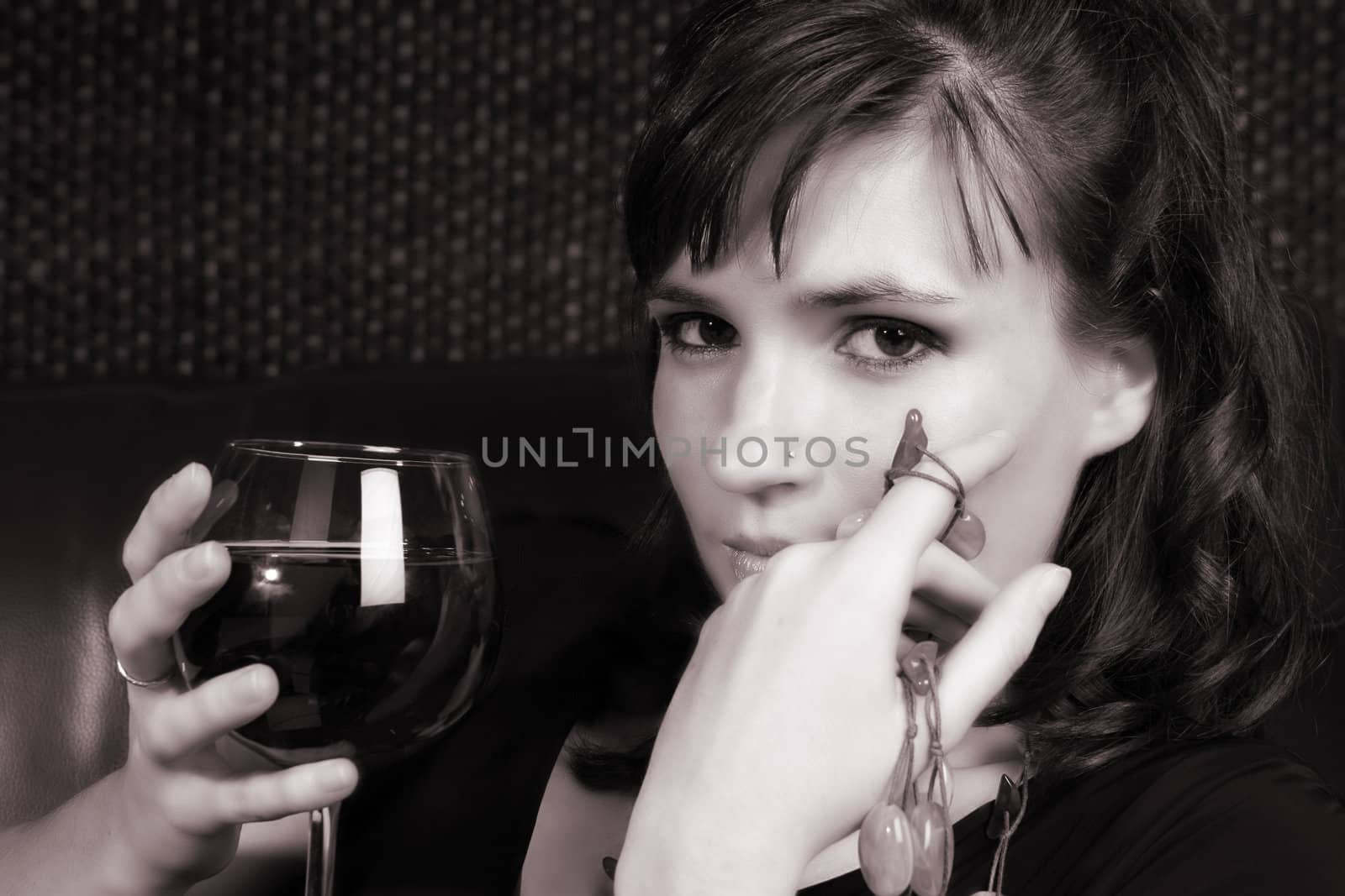 Female model with intense eyes holding a glass of red wine
