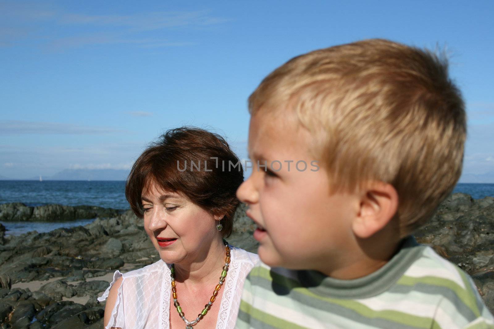 Beatiful grandmother and grandson playing on the beach