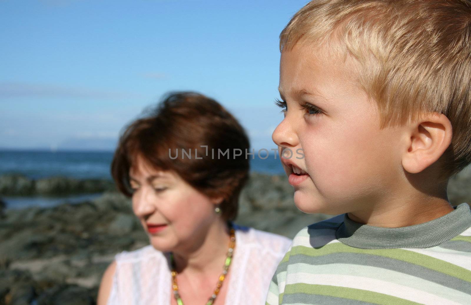 Beatiful grandmother and grandson playing on the beach