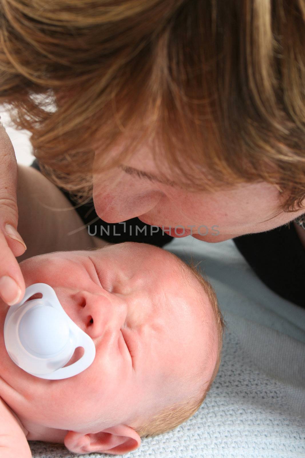Worried mother and crying newborn baby with dummy