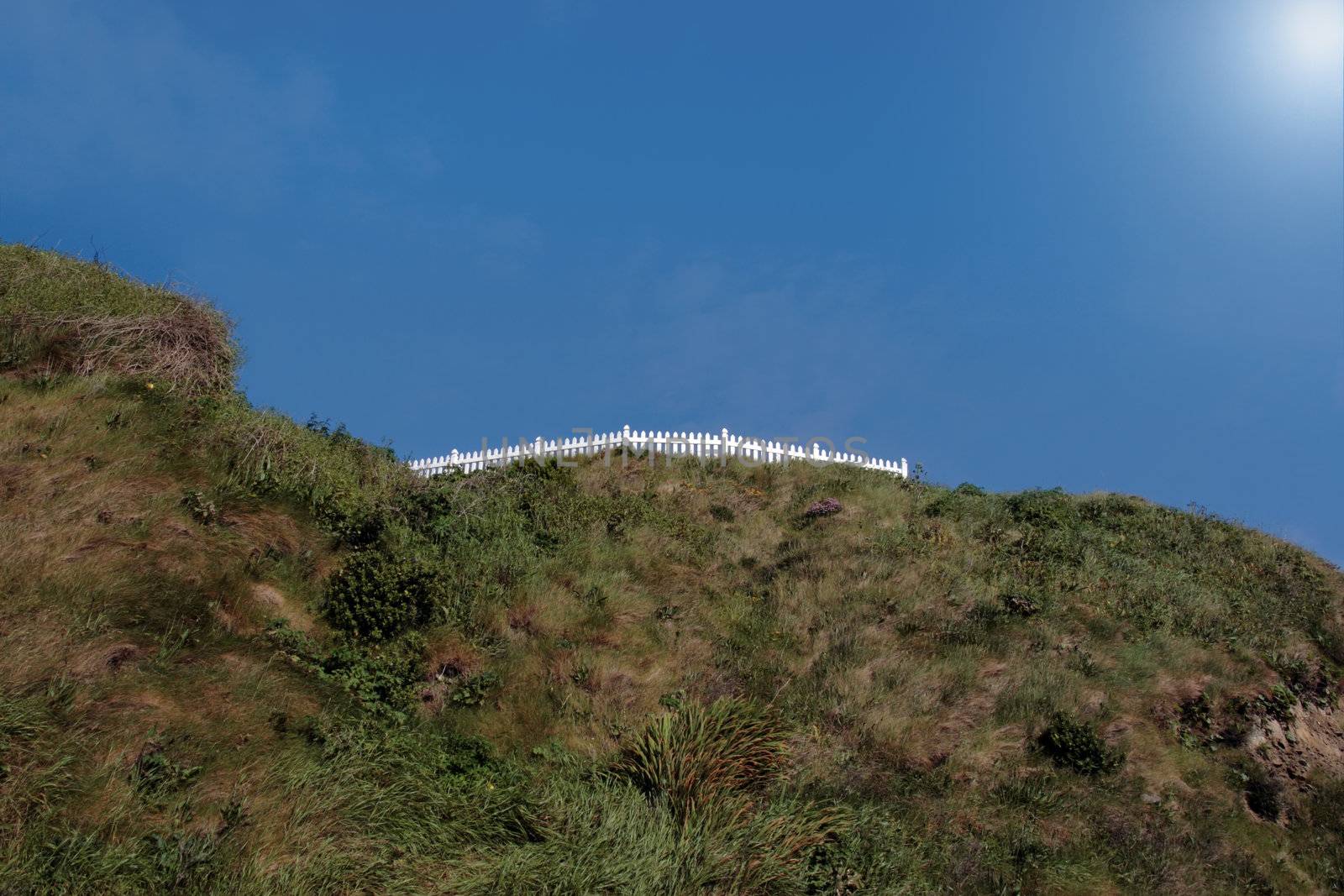 a white picket fence on top of a hill