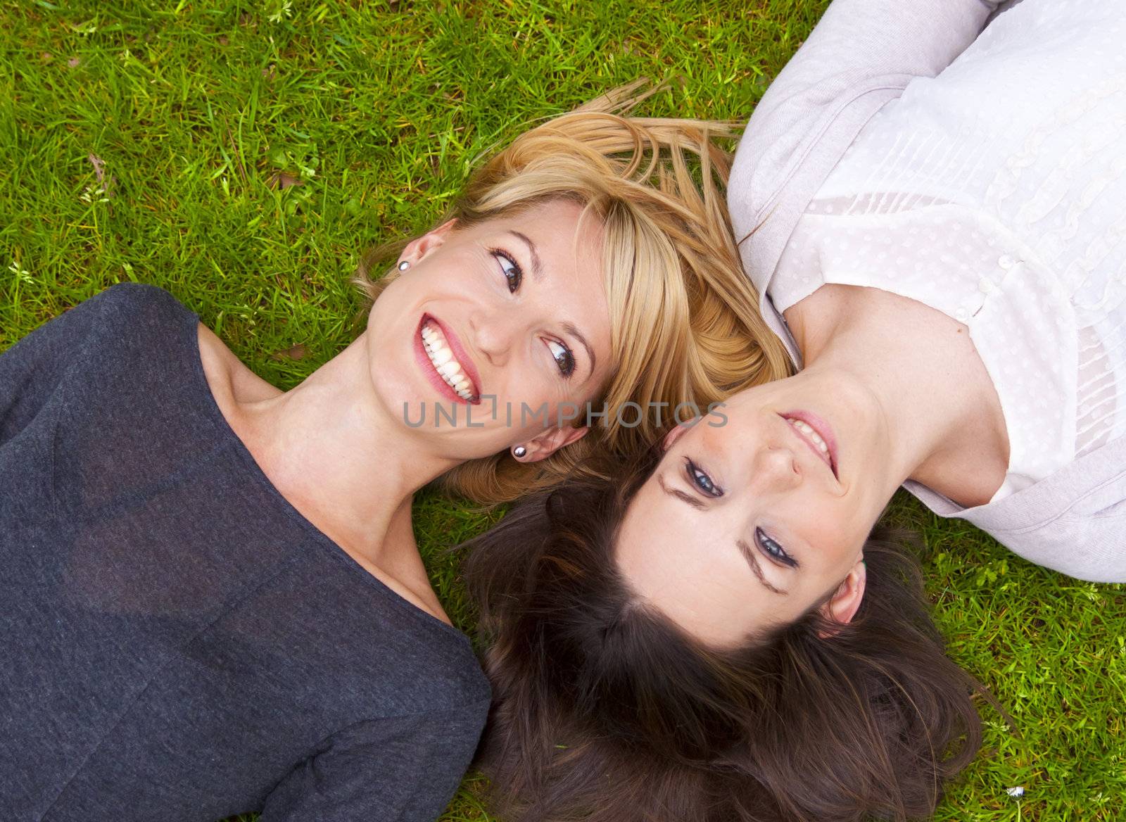 Two girls lying in the grass by kasto