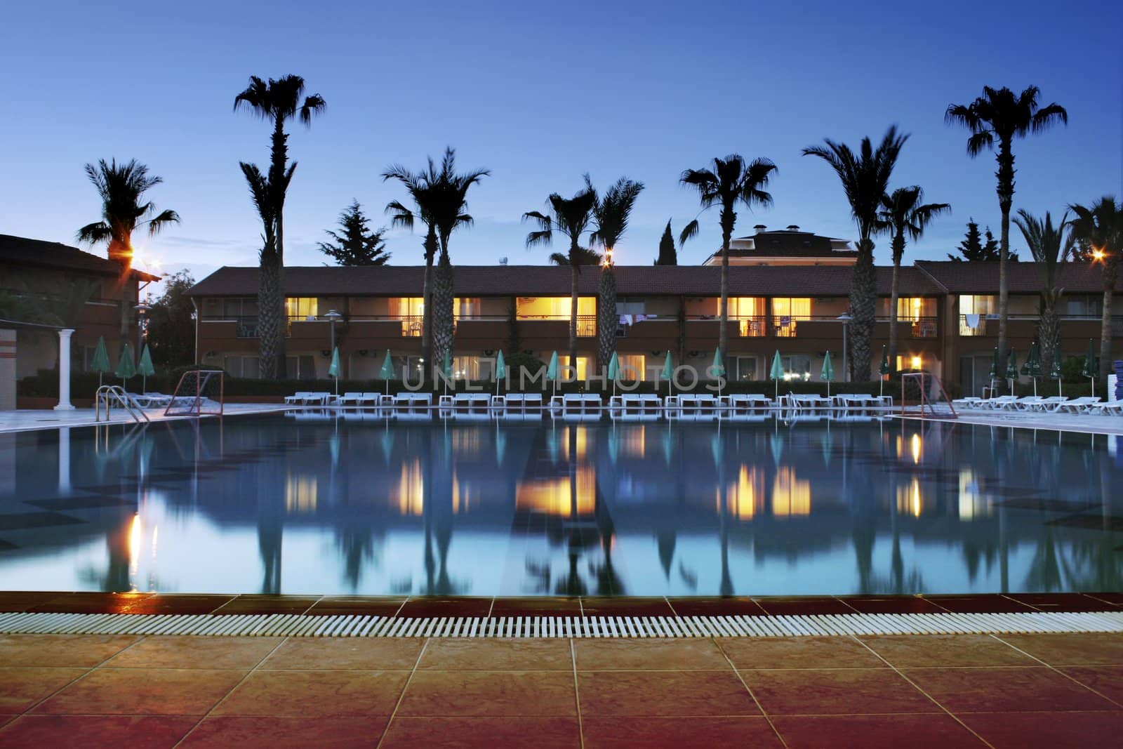 Night time photo of a swimming pool at a mediterranean resort.