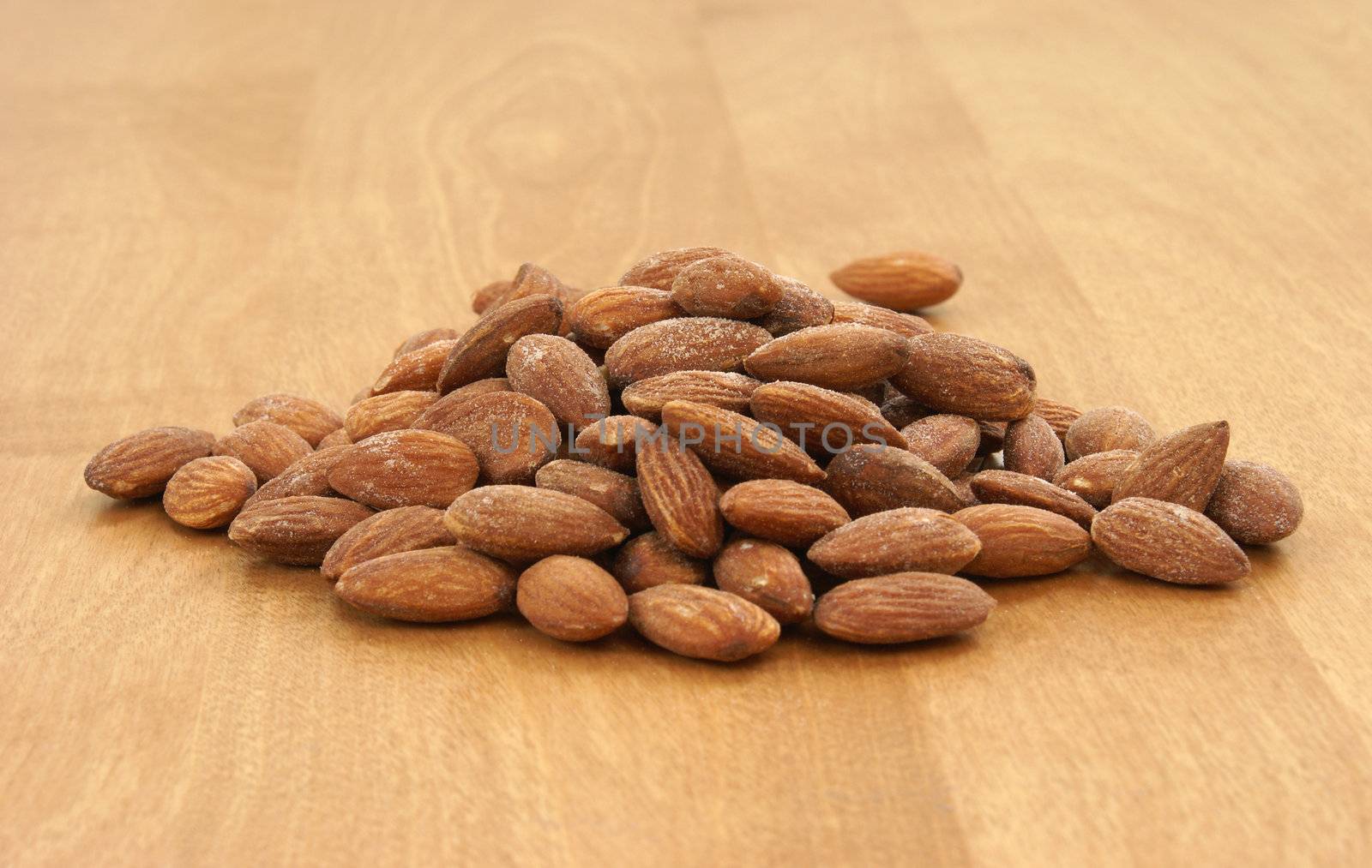 A pile of almonds on a wood background.