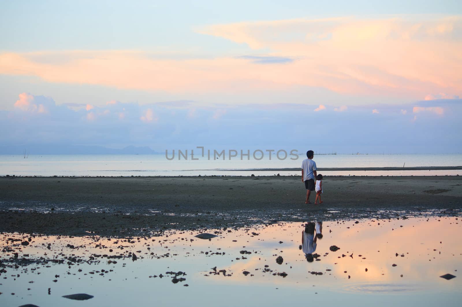 father and daughter taking an early morning walk on a low tide sea shore