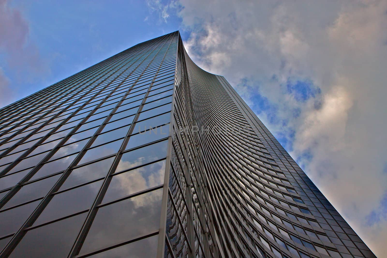 Close up of building with futuristic curved wall against a blue and cloudy sky