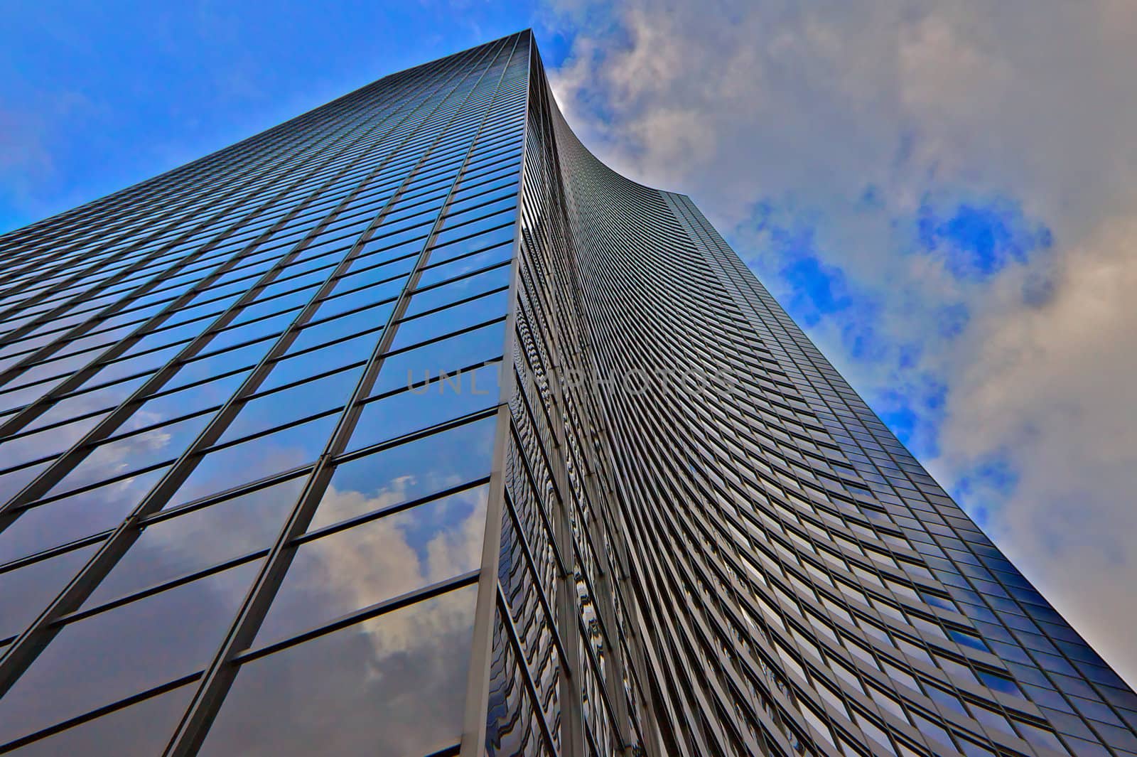 Close up of building with futuristic curved wall against a blue and cloudy sky