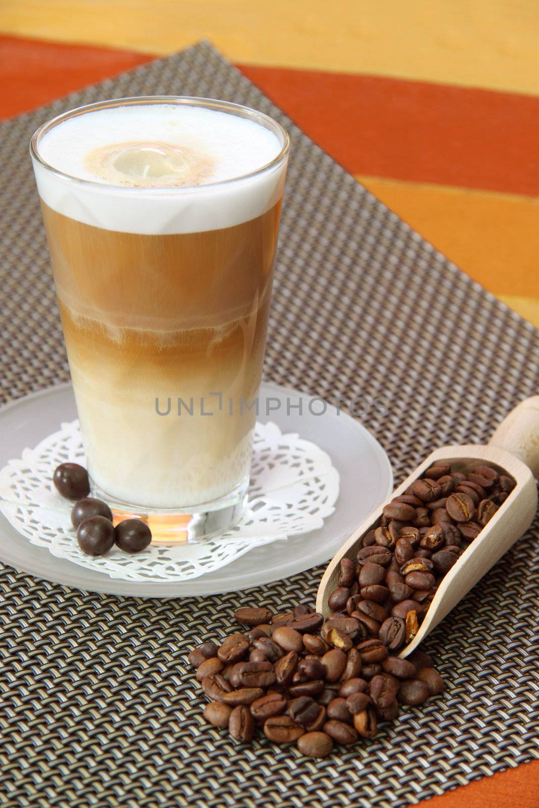 Latte Macchiato in glass with coffee grain on brown background