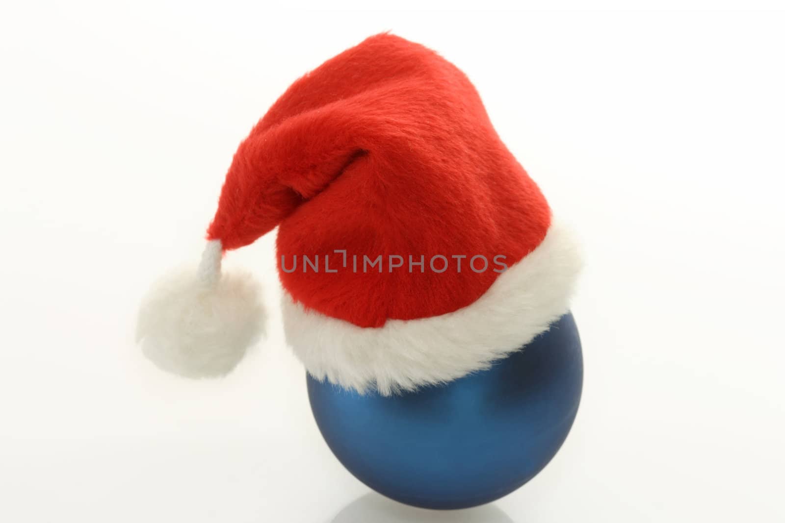 Christmas ball with santa claus cap on bright background. Shot in studio.